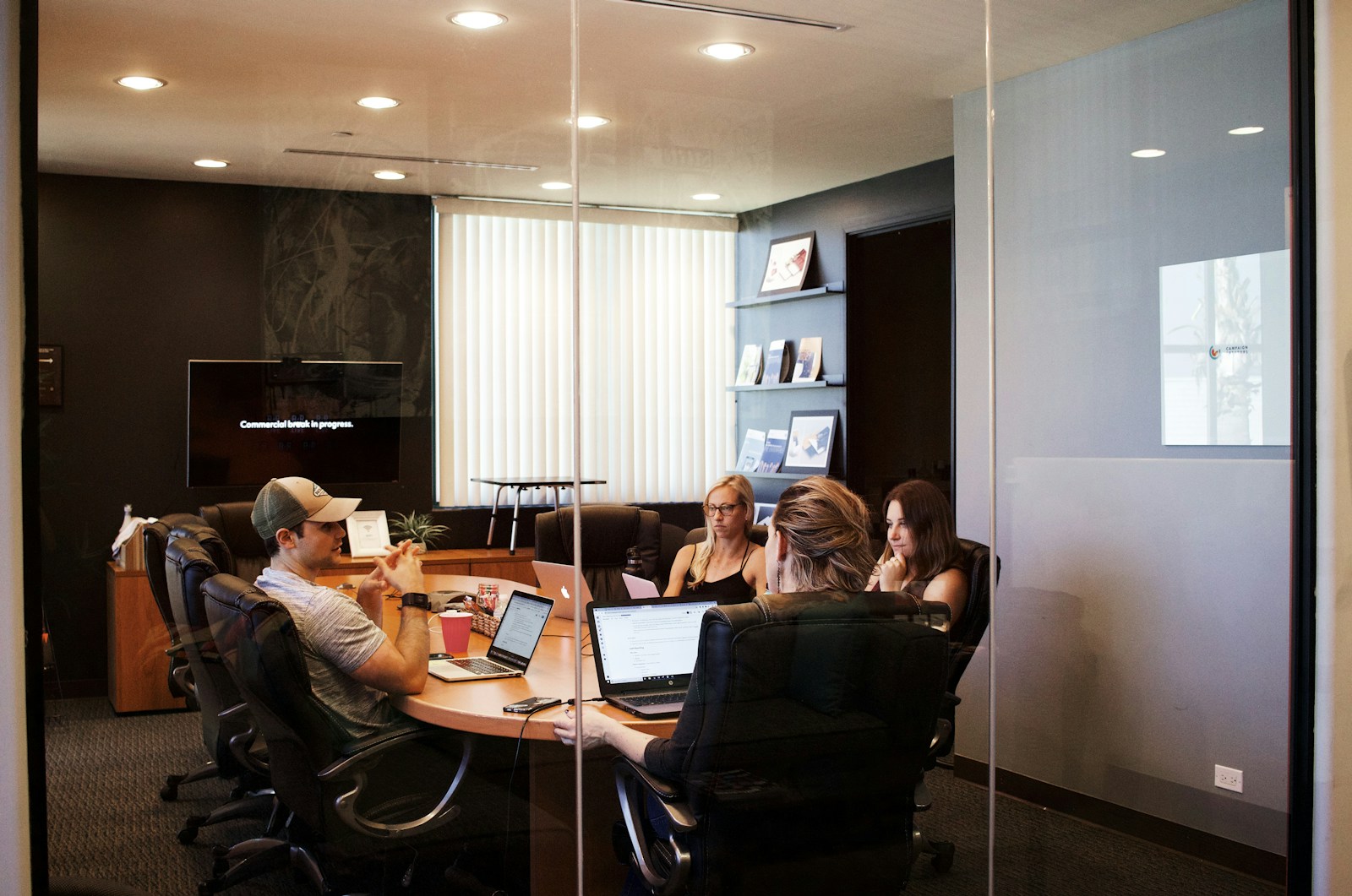 Colleagues talking around a table with their laptops open